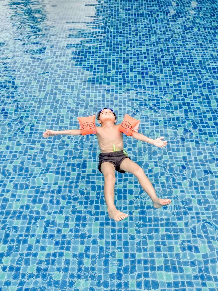 Boy floating on his back in a pool with arm floats