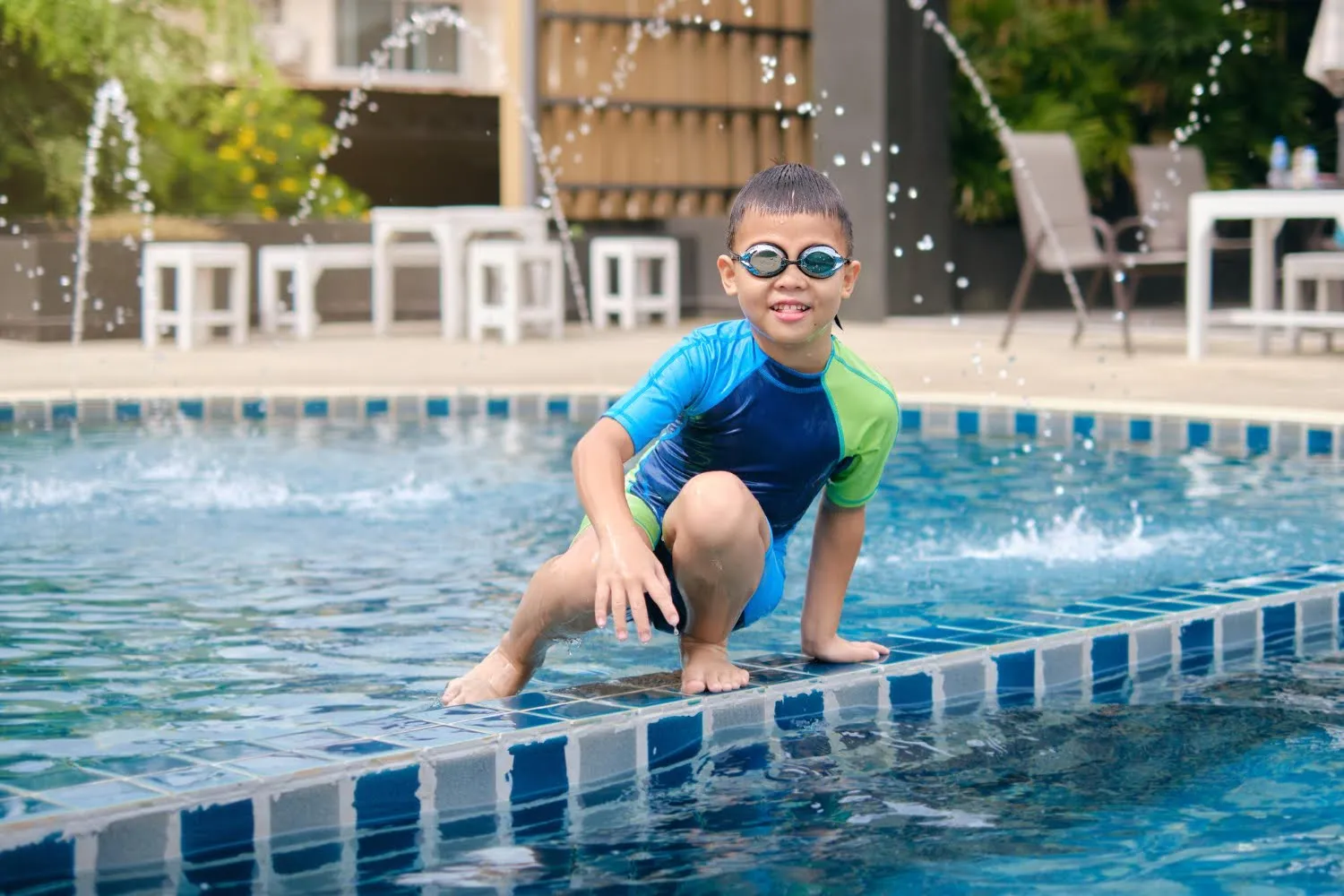 Boy in goggles climbing out at the pool edge