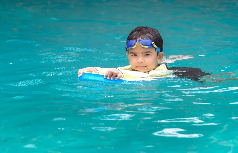 Boy learning to swim with a kickboard