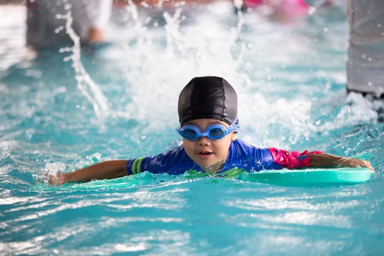 Boy kicking with a kickboard during a swimming lesson