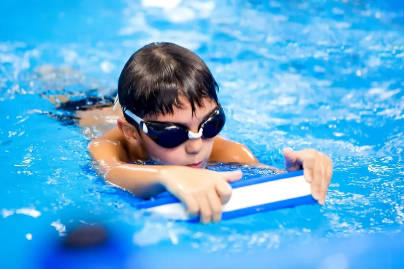 Boy in goggles training with a kickboard