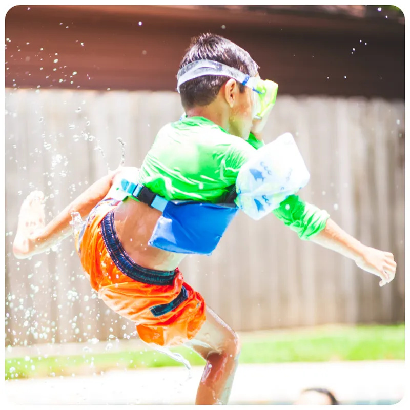 Boy with arm floats jumping into a pool