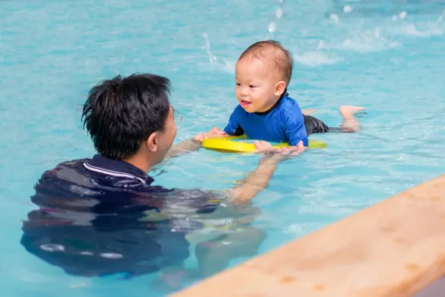 Coach teaching a baby to swim with a float