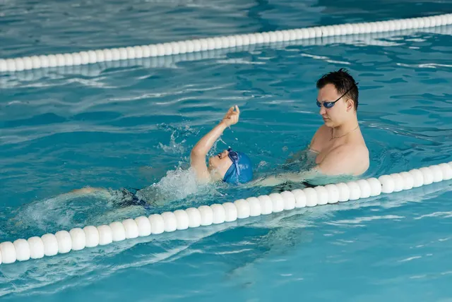 Coach teaching a boy to swim in a pool lane