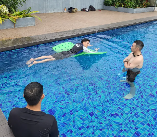 Coach watching an adult swimmer with a kickboard in a condo pool