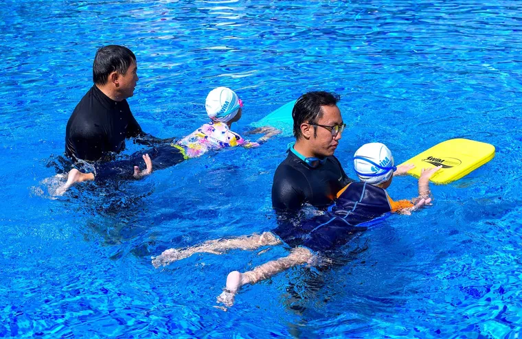 SwimSafe coaches teaching two children with kickboards