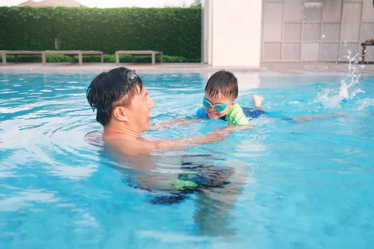 Father swimming with his young son in a pool