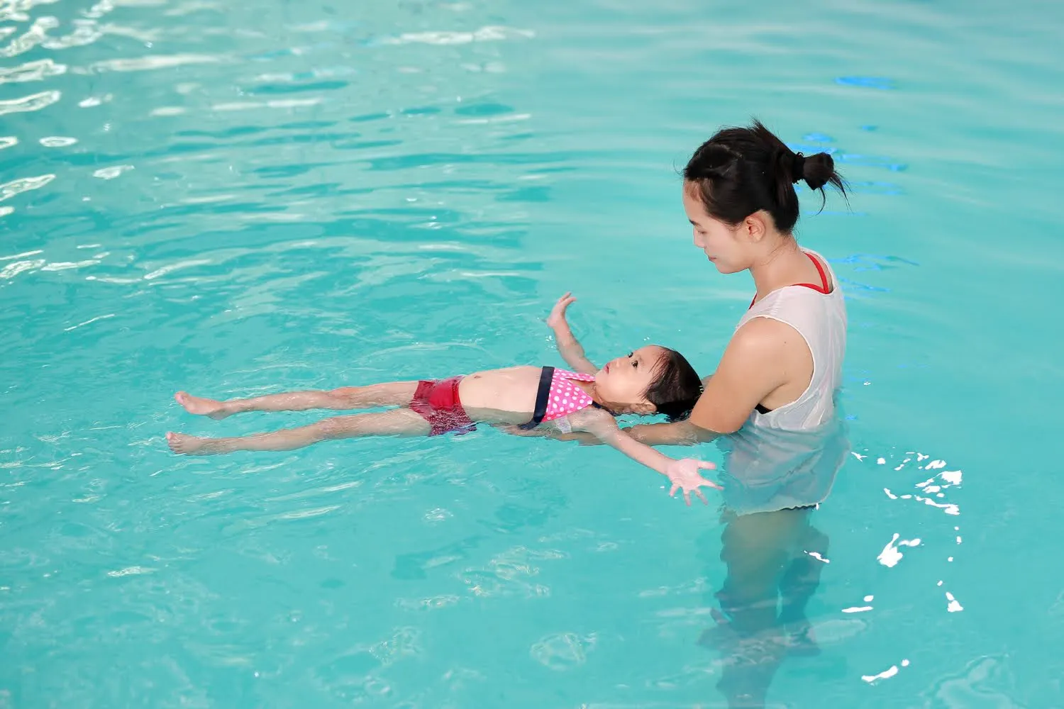 Female coach teaching a girl to float on her back