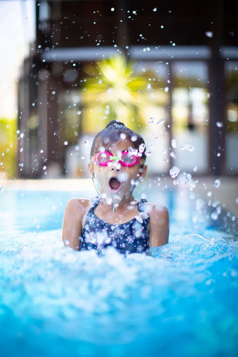 Girl in goggles splashing in a pool