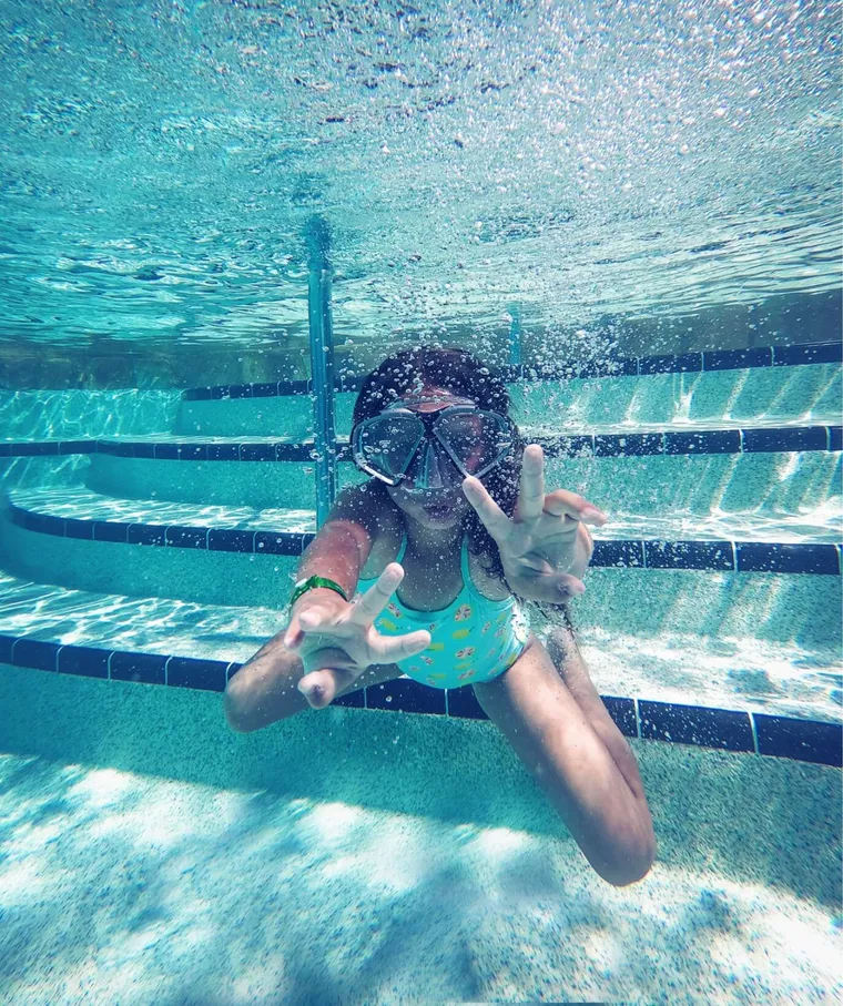Girl swimming underwater and waving