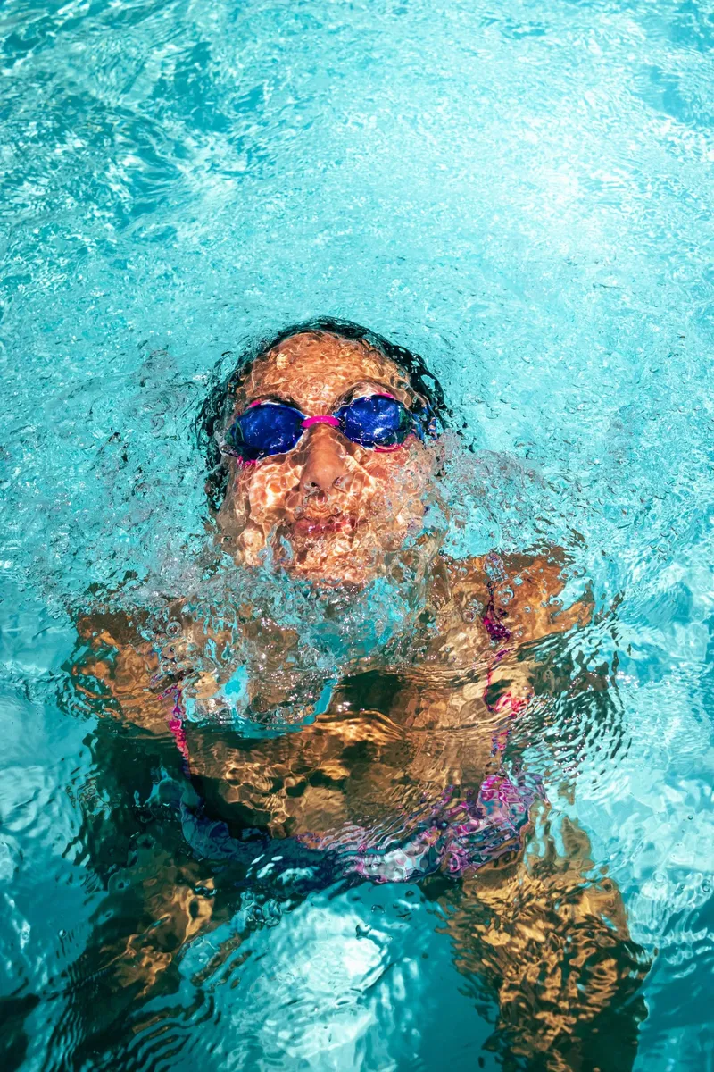 Girl swimming underwater in goggles