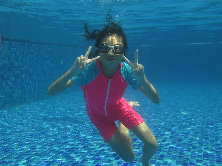 Girl underwater making a peace sign