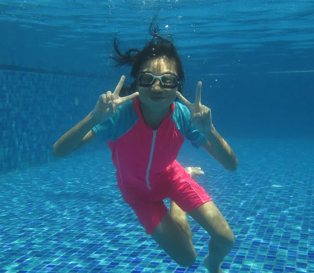 Girl underwater making a peace sign during a swimming lesson