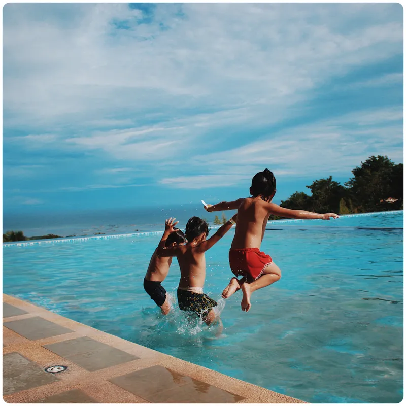 Kids jumping into an infinity pool
