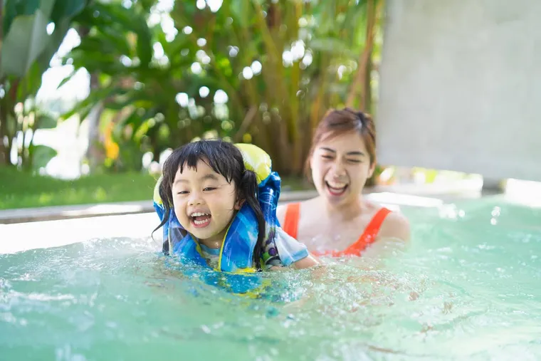 Mother with her child in a life vest in the pool