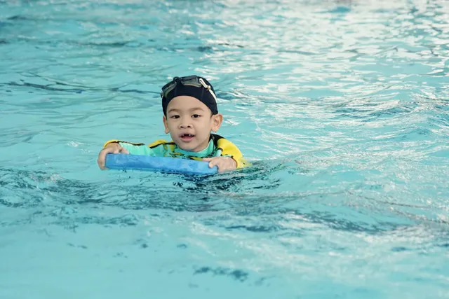 Smiling boy swimming with a foam pad