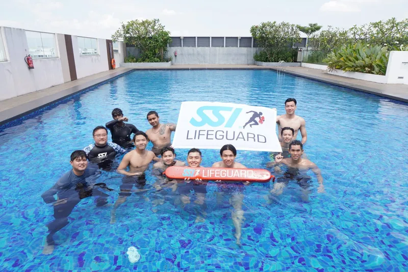 SSI lifeguard course graduates in the pool with a lifeguard banner