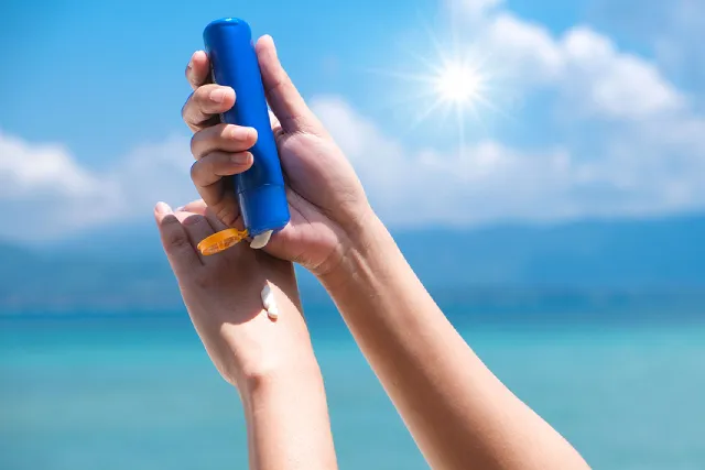 Hand holding a sunscreen tube under the sun