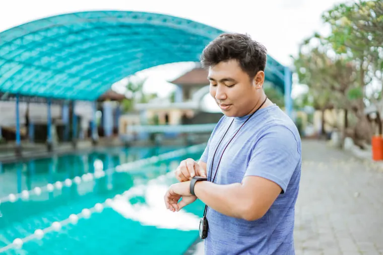 Swimming coach checking a stopwatch at the poolside