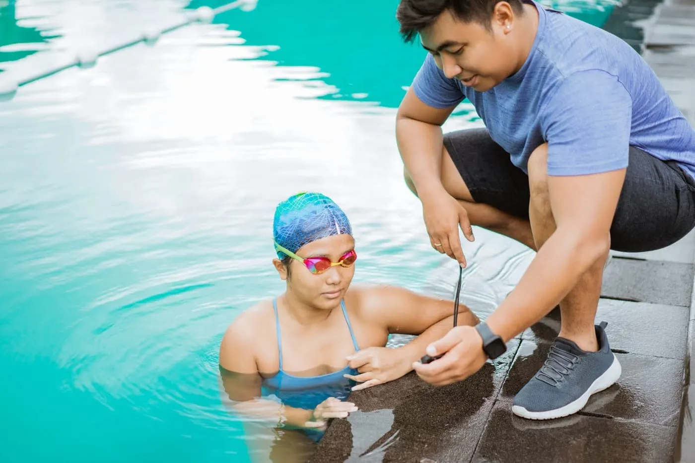 Swimming coach timing a swimmer at the pool edge