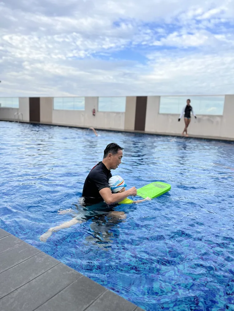 Swimming coach with a kickboard in a rooftop condo pool
