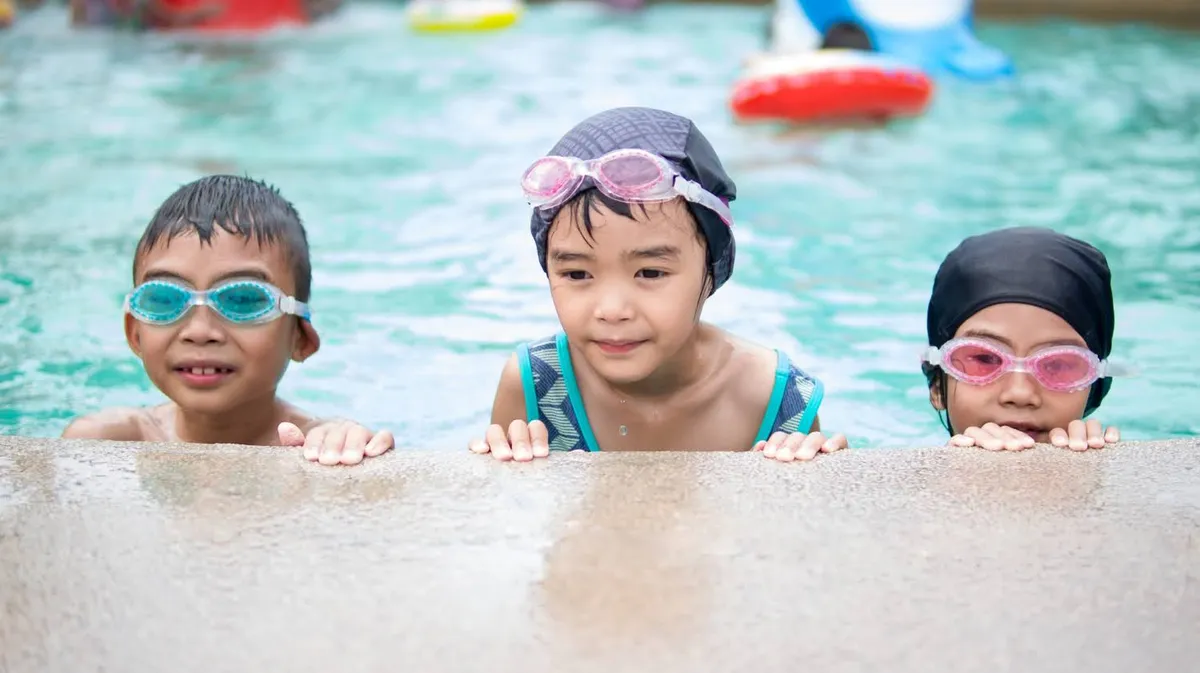Three kids in goggles at the pool edge