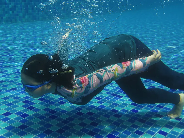 Woman in a full-coverage swimsuit swimming underwater